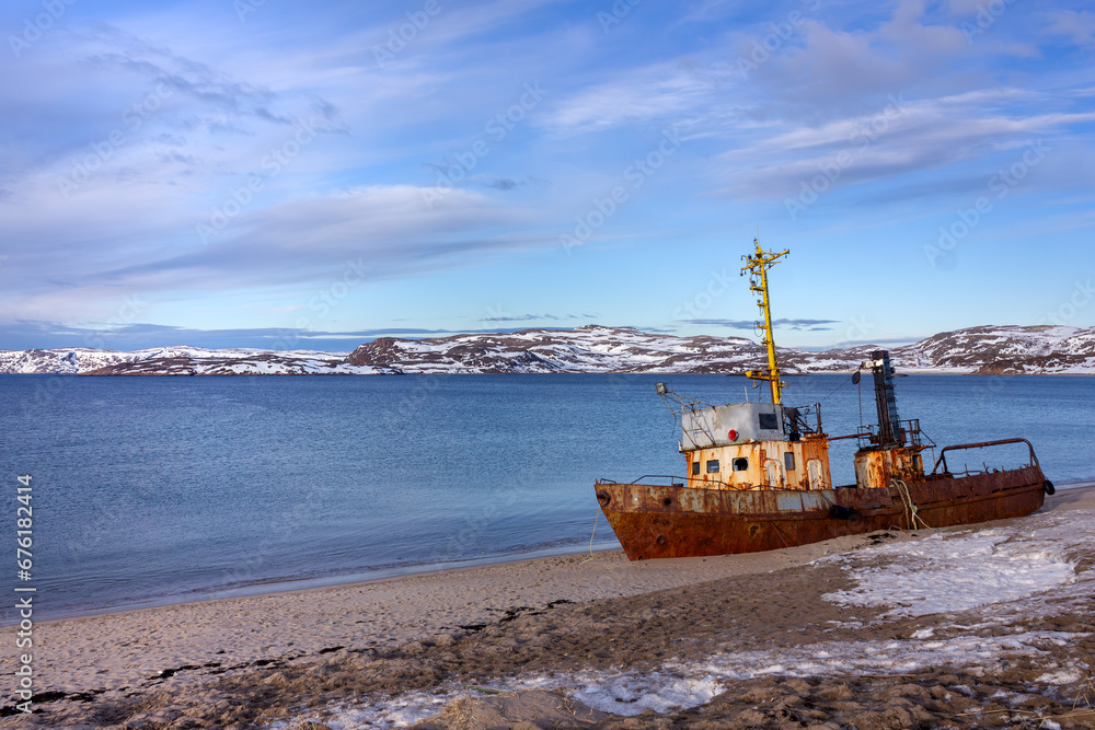 An old rusty fishing boat washed ashore in the Barents Sea of the Arctic Ocean in Teriberka close-up