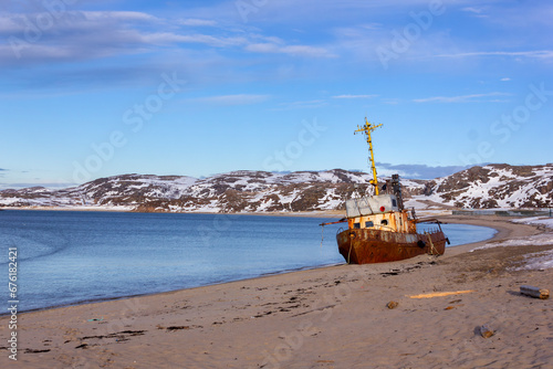 An old rusty fishing boat washed ashore in the Barents Sea of the Arctic Ocean in Teriberka close-up