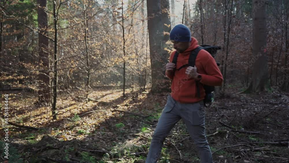 Outdoor adventurer man hiking through woods with backpack, way in wilderness. Backpacking alone on autumn forest paths. Trekking concept. Traveller walking in fall woods. Enjoying Scandinavian nature Outdoor adventurer man hiking through woods with backpack, way in wilderness. Backpacking alone on autumn forest paths. Trekking concept. Traveller walking in fall woods. Enjoying Scandinavian nature