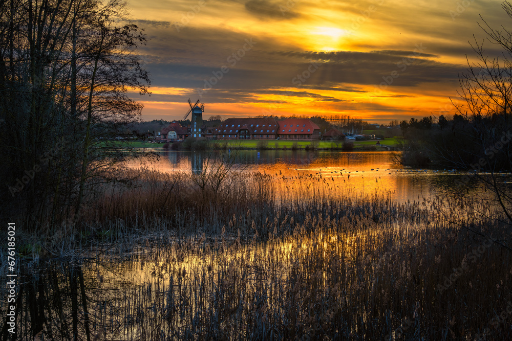 Caldecott lake at sunset with traditional windmill in the background