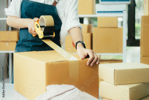 Online entrepreneur using scotch tape to seal parcel box.