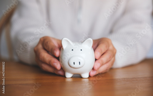 Closeup image of a woman holding a piggy bank for saving money and financial concept