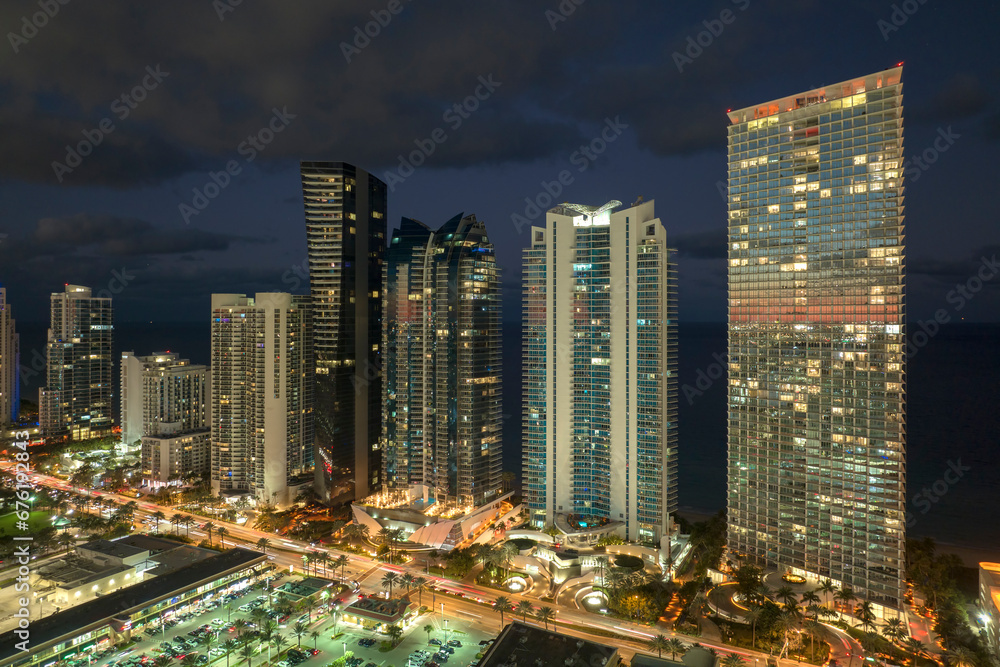 Obraz premium Night urban landscape of downtown district in Sunny Isles Beach city in Florida, USA. Skyline with brightly illuminated streets and high skyscraper buildings in modern american megapolis