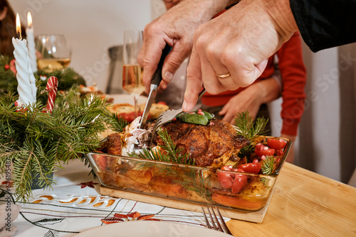 Christmas family dinner  Christmas decor  holiday table top view  celebrating the new year together  spread a hot dish  turkey leg  chicken in plates  close-up of hands cutting roast turkey