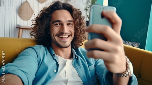 Close up young smiling happy man in casual clothes doing selfie shot pov on mobile phone sitting on blue sofa at home flat indoors rest relax on weekends free time. People lounge lifes : Generative AI photo
