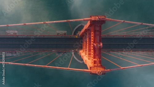 Overhead view of Golden Gate Bridge, San Francisco in misty golden sunset light. View from top to bottom deep blue ocean and tall red construction of California landmark USA Golden Gate Bridge aerial
