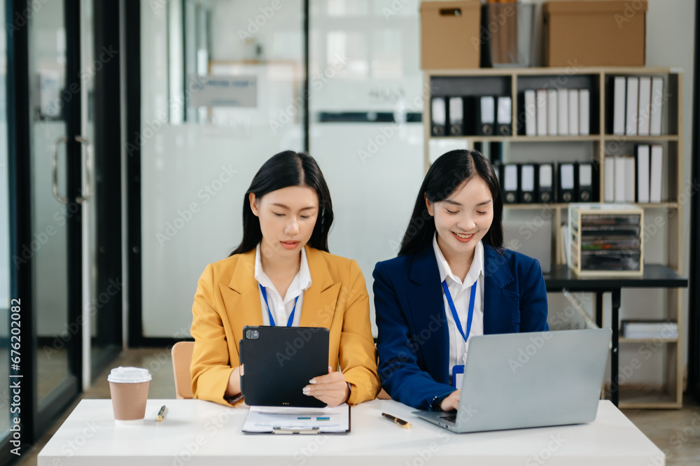 Asian business colleague business presents and explains and using laptop and tablet. Teamwork, financial marketing team, while sitting Asian business colleague business presents and explains and using laptop and tablet. Teamwork, financial marketing team, while sitting
