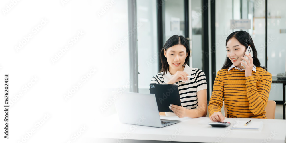 Two Asian businesswoman discuss investment project working and planning strategy with tablet laptop computer Two Asian businesswoman discuss investment project working and planning strategy with tablet laptop computer