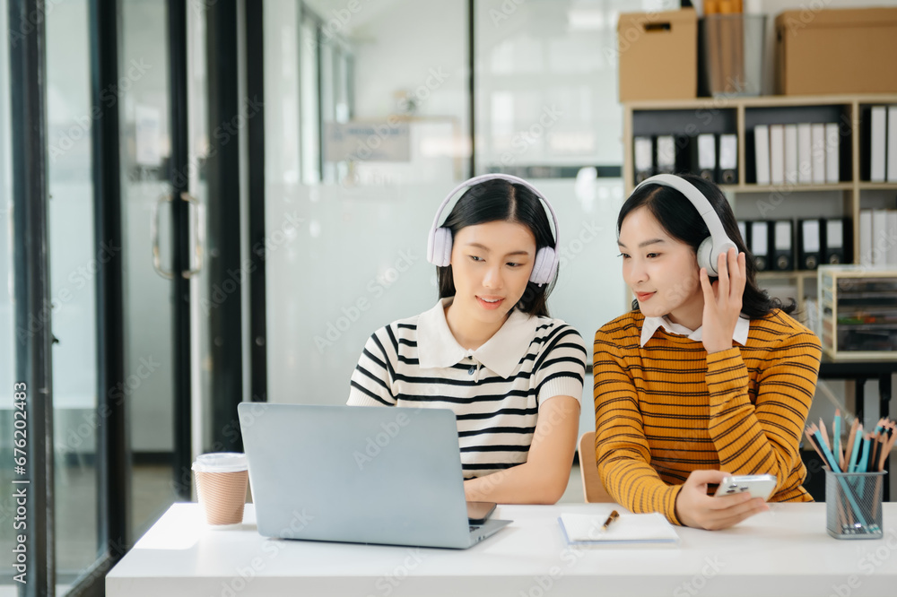 Two Attractive young Asian female college students working on the school project using laptop computer and tablet together, enjoy talking Two Attractive young Asian female college students working on the school project using laptop computer and tablet together, enjoy talking