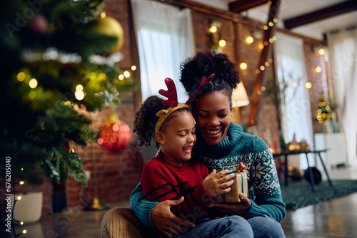 Konstfotografi Happy black mother giving her daughter present on Christmas eve.