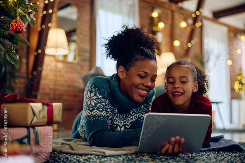 Happy black mother and daughter using digital tablet at Christmas at home. photo
