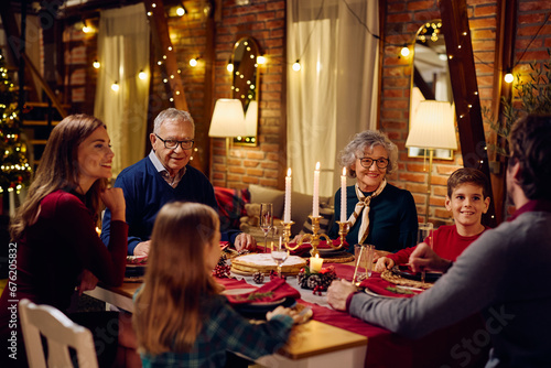 Happy multigeneration family talks during Christmas dinner at dining table.