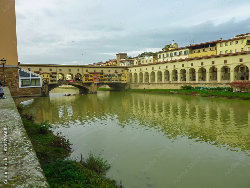 Scenic view of historic medieval Ponte Vecchio bridge with shops spanning the Arno River, Florence, Tuscany, Italy, Europe. Landmark in Italian city on cloudy overcast day. Tourist travel destination