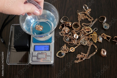 Wallpaper Mural pawnshop worker determines the ring of gold jewelry using the Hydrostatic weighing method by Archimedes' law, evaluation of gold items in a pawnshop, fake gold Torontodigital.ca