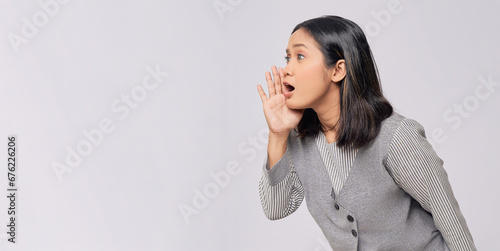 Beautiful young Asian woman in casual clothes holding a hand near mouth, telling a secret, whispering gossip isolated on white background. People lifestyle emotion concept