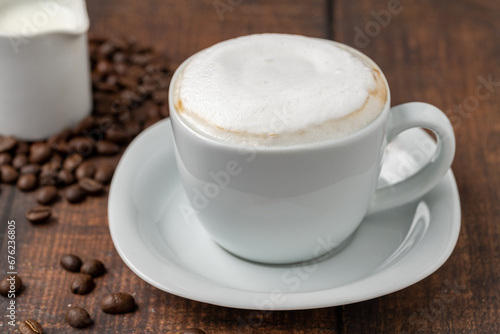 Cappuccino coffee in a white porcelain cup on a wooden table