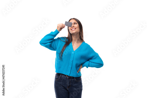 charming cute young woman dressed in a blue pullover holds a banking plastic card