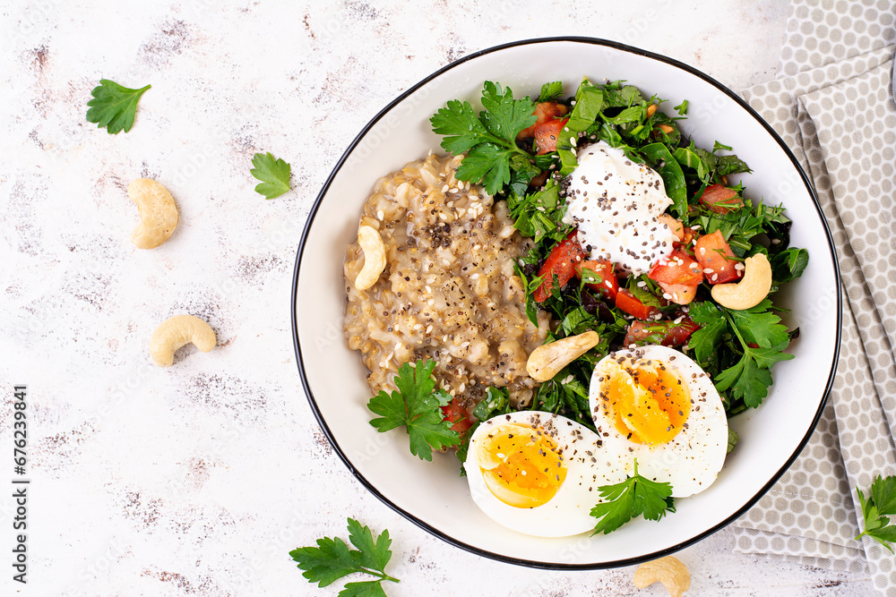 Breakfast oatmeal porridge with boiled eggs and fresh salad. Healthy balanced food. Trendy food. Top view