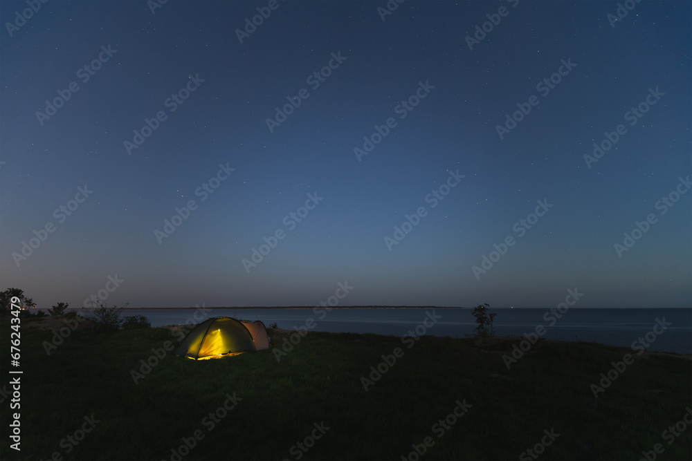 Wild camping with a tent at night in summer. Starry sky, Paldiski cliff.