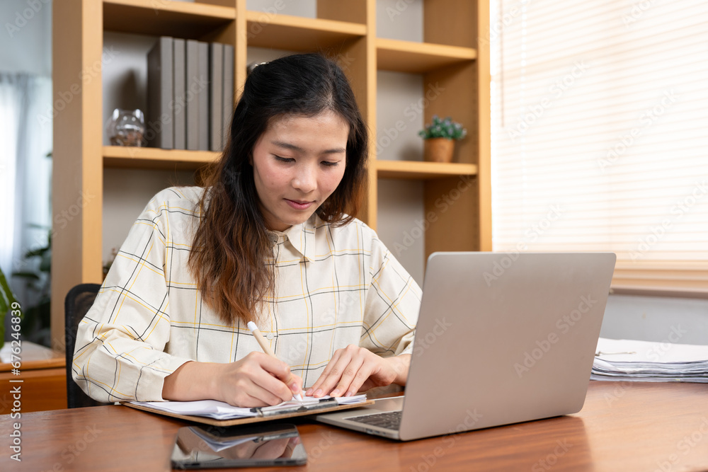 Young adult asian woman stay at home writing work and study. Workplace table with laptop computer and book. Domestic asia room lifestyles.