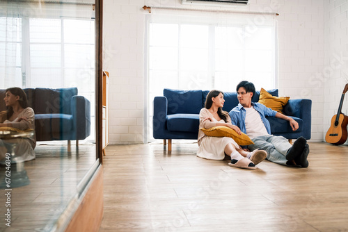 An attractive married man holding a tablet and a woman sit on the floor together in the living room looking at the camera at the new home. A family spends quality time together after home moving.