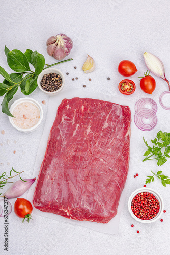 Dry aged Bavette steak with traditional spices and herbs. Fresh raw meat cut, light stone background photo