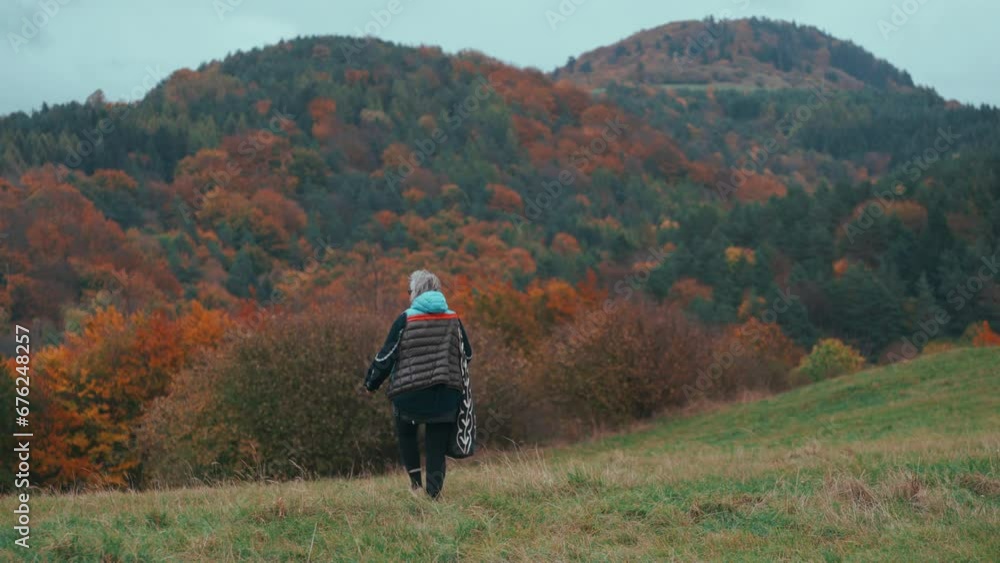 Medium shot of an older female Photographer with grey hair walking and ...