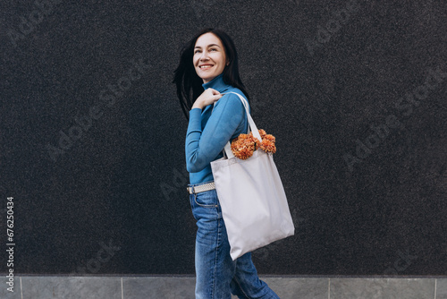 Young woman with white tote cotton bag on her shoulder. Mockup and zero waste concept.