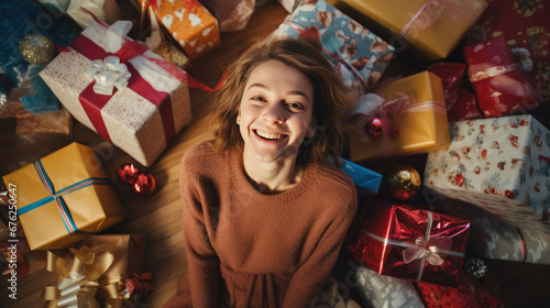A happy beautiful girl with lots of Christmas presents or gifts around her, smiling and looking at a camera, ariel view, Xmas hoiday and celebration.n.
