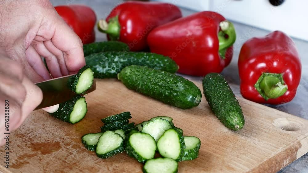 Slice the cucumber with a santoku knife on a cutting board. Slow motion Slice the cucumber with a santoku knife on a cutting board. Slow motion