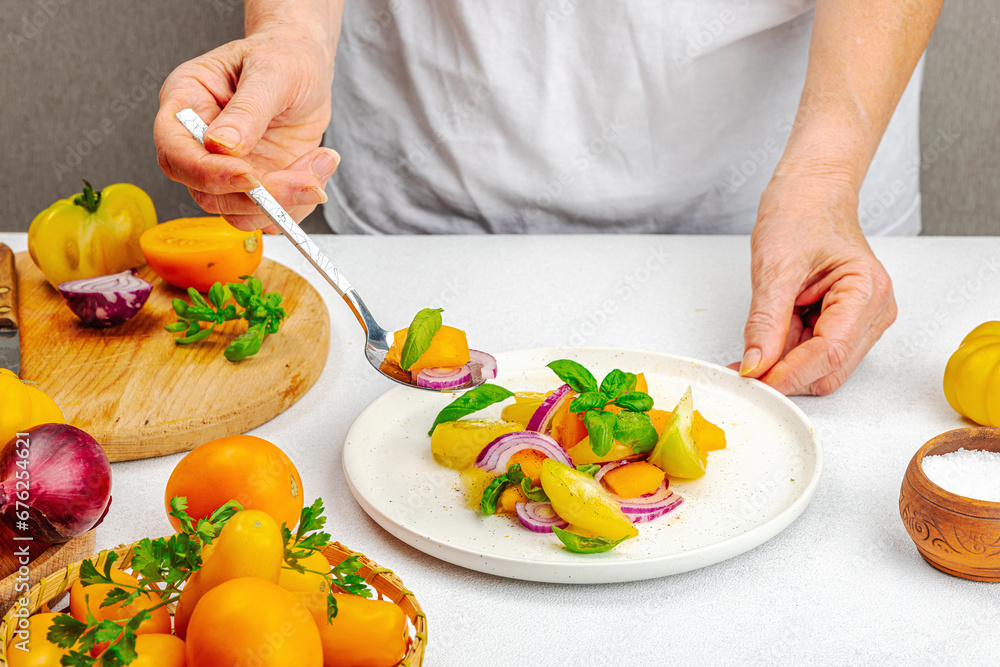 A woman is preparing a tomato salad. Ripe vegetables, herbs, aromatic spices, olive oil A woman is preparing a tomato salad. Ripe vegetables, herbs, aromatic spices, olive oil