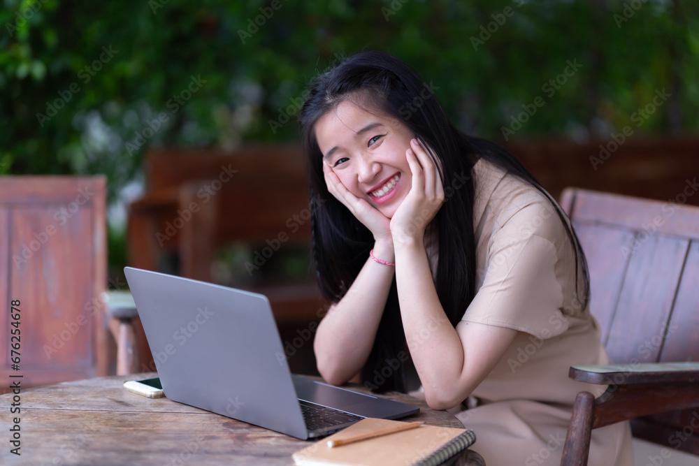 Happy of Young asian teen girl college student using laptop computer writing on pc working from at the cafe.Online education, elearning concept,freelance people businessfemale Happy of Young asian teen girl college student using laptop computer writing on pc working from at the cafe.Online education, elearning concept,freelance people businessfemale