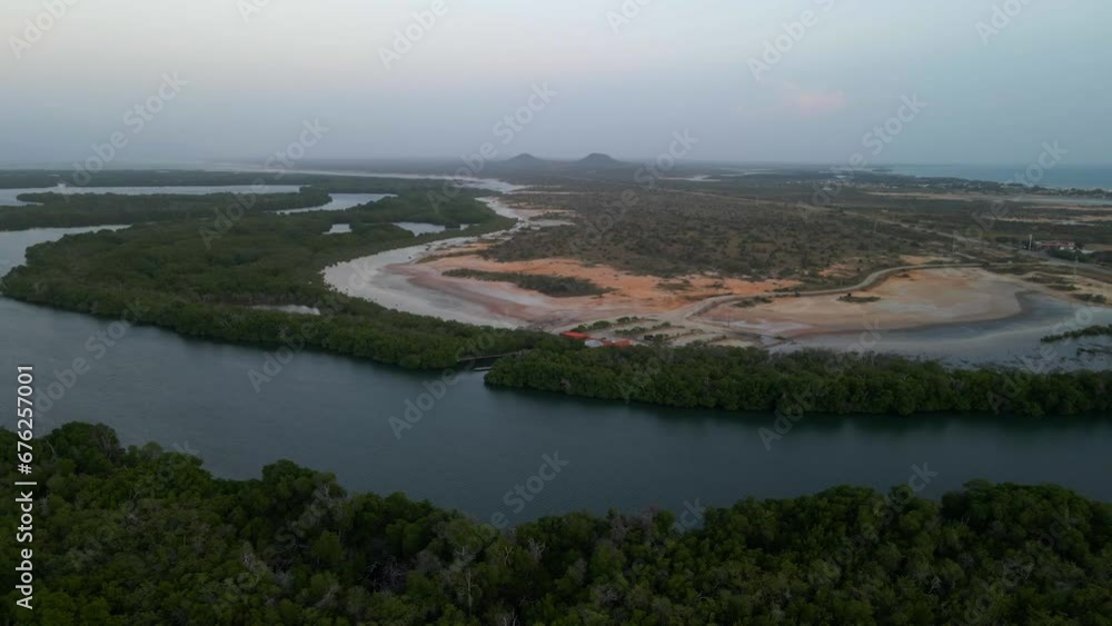 Drone flies above a mangrove forest crossing an extended estuarine river revealing a shoreline, beautiful horizon with Tetas de Maria Guevara mountains, Porlamar, Margarita Island, Venezuela Drone flies above a mangrove forest crossing an extended estuarine river revealing a shoreline, beautiful horizon with Tetas de Maria Guevara mountains, Porlamar, Margarita Island, Venezuela