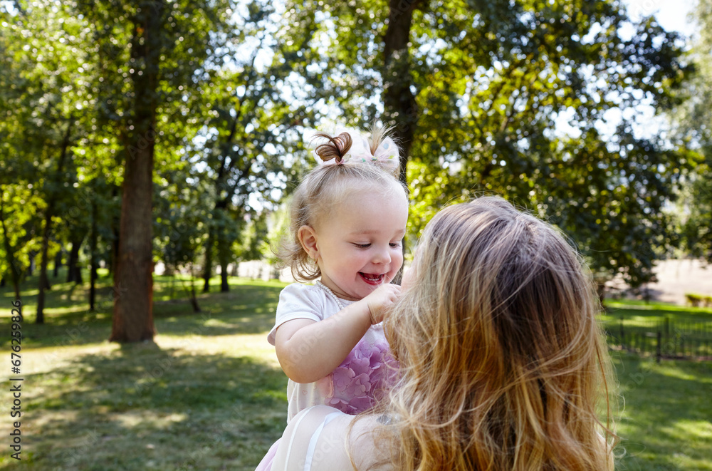 Mother and daughter walk in the summer city park. Childhood, leisure and people concept - happy family rest on nature and have a good time Mother and daughter walk in the summer city park. Childhood, leisure and people concept - happy family rest on nature and have a good time
