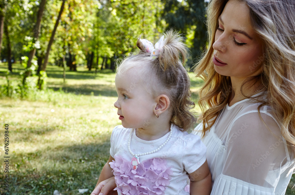 Mother and daughter walk in the summer city park. Childhood, leisure and people concept - happy family rest on nature and have a good time