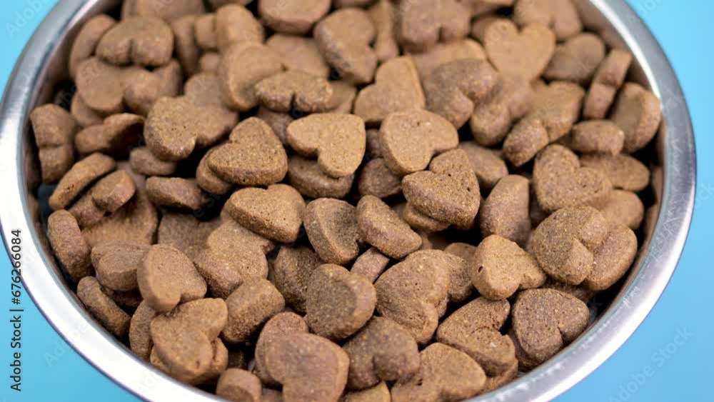 Dog food bowl with heart-shaped bits, gently swirling on a blue canvas. Love for animals. Dog food bowl with heart-shaped bits, gently swirling on a blue canvas. Love for animals.