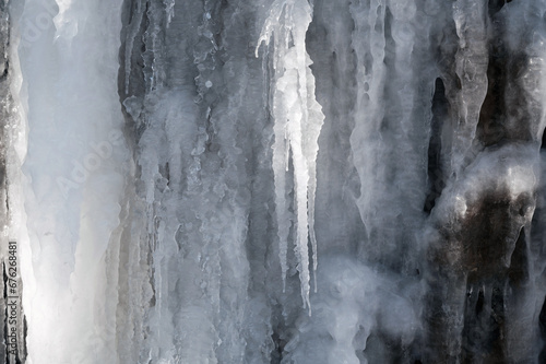frozen icicles and icing on a stone wall in winter close-up