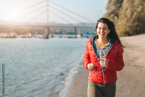 Beautiful young woman with closed eyes running on the beach in the morning and smiling while recalling her favorite old memories.