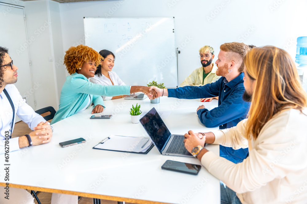 Multi-ethnic people shaking hands sitting on a coworking room