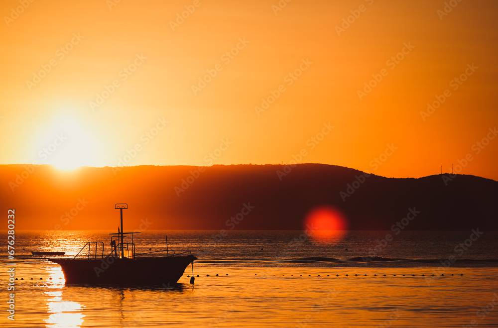 Silhouette of a yacht in the sea at dusk. Beautiful landscape photo of a motor boat in Adriatic sea at sunset