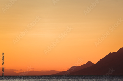 Silhouette of Adriatic sea coastline at sunset. Beautiful landscape of mountains silhouette and water surface © hurricanehank