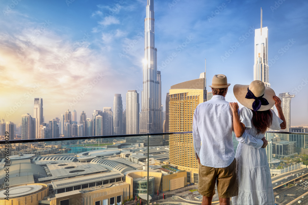 A couple on holidays enjoys the panoramic view over the city skyline of Dubai, UAE, during sunrise - obrazy, fototapety, plakaty 