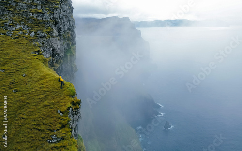 Hiker standing on edge of famous rock cliff. Concept: Adventure, Explore, Hike, Lifestyle. Faroe Islands. Dramatic weather