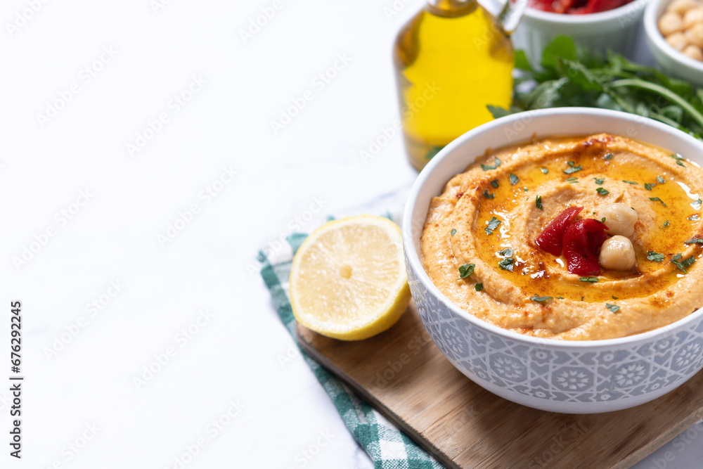 Roasted red pepper hummus in white bowl on white marble background. Copy space Roasted red pepper hummus in white bowl on white marble background. Copy space