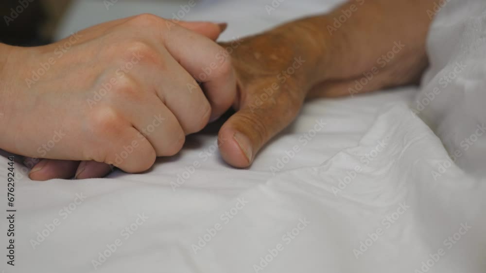 Girl takes and gently touches hand of sick mature woman lying in bed hospital. Granddaughter comforts wrinkled arm of her elderly grandmother in medical clinic. Daughter gives support to her mother Girl takes and gently touches hand of sick mature woman lying in bed hospital. Granddaughter comforts wrinkled arm of her elderly grandmother in medical clinic. Daughter gives support to her mother