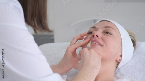 A beautiful woman receives injections in her lips from a professional doctor. Lip augmentation. Cosmetic procedures photo