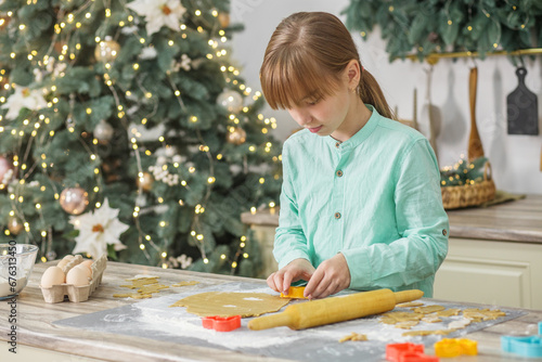 Preteen girl cooking Christmas gingerbread cookies in cozy home kitchen. Family traditions.