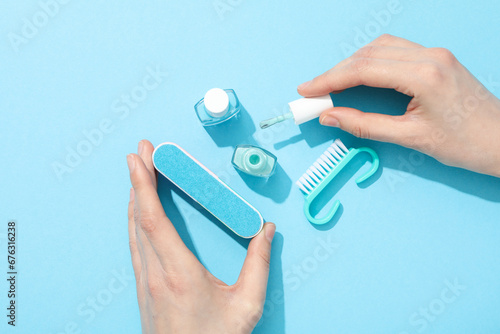 Tools for manicure and female hands on blue background, top view