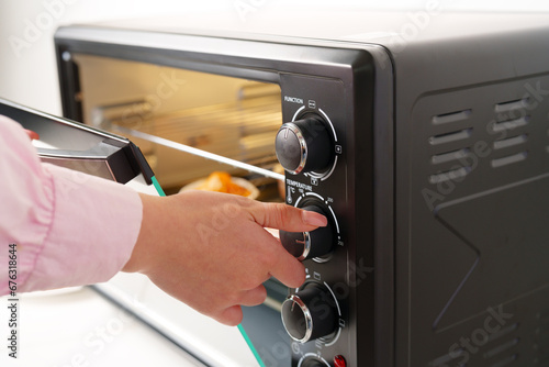 Woman's hands taking buscuit cupcakes out of mini oven photo