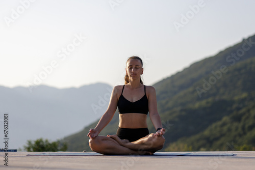 Young woman meditating at outdoor yoga workout in the morning